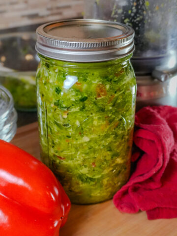 epis in a glass mason jar with kitchen equipment in the background and with whole red bell pepper laid next to it.