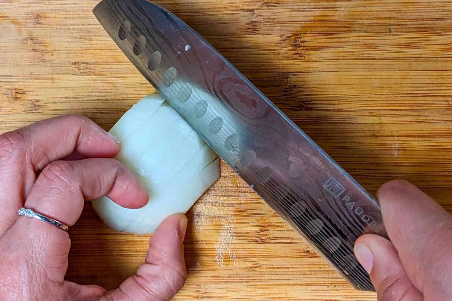 slicing the sliced halved onion perpendicular to the slices.