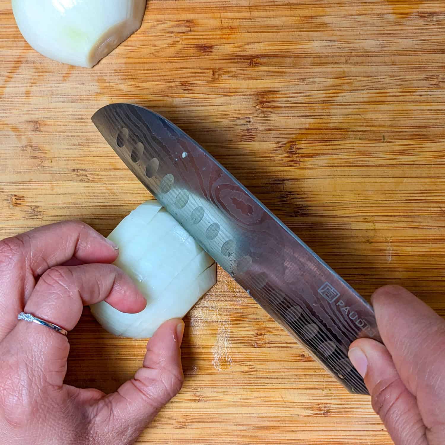 slicing the sliced halved onion perpendicular to the slices.