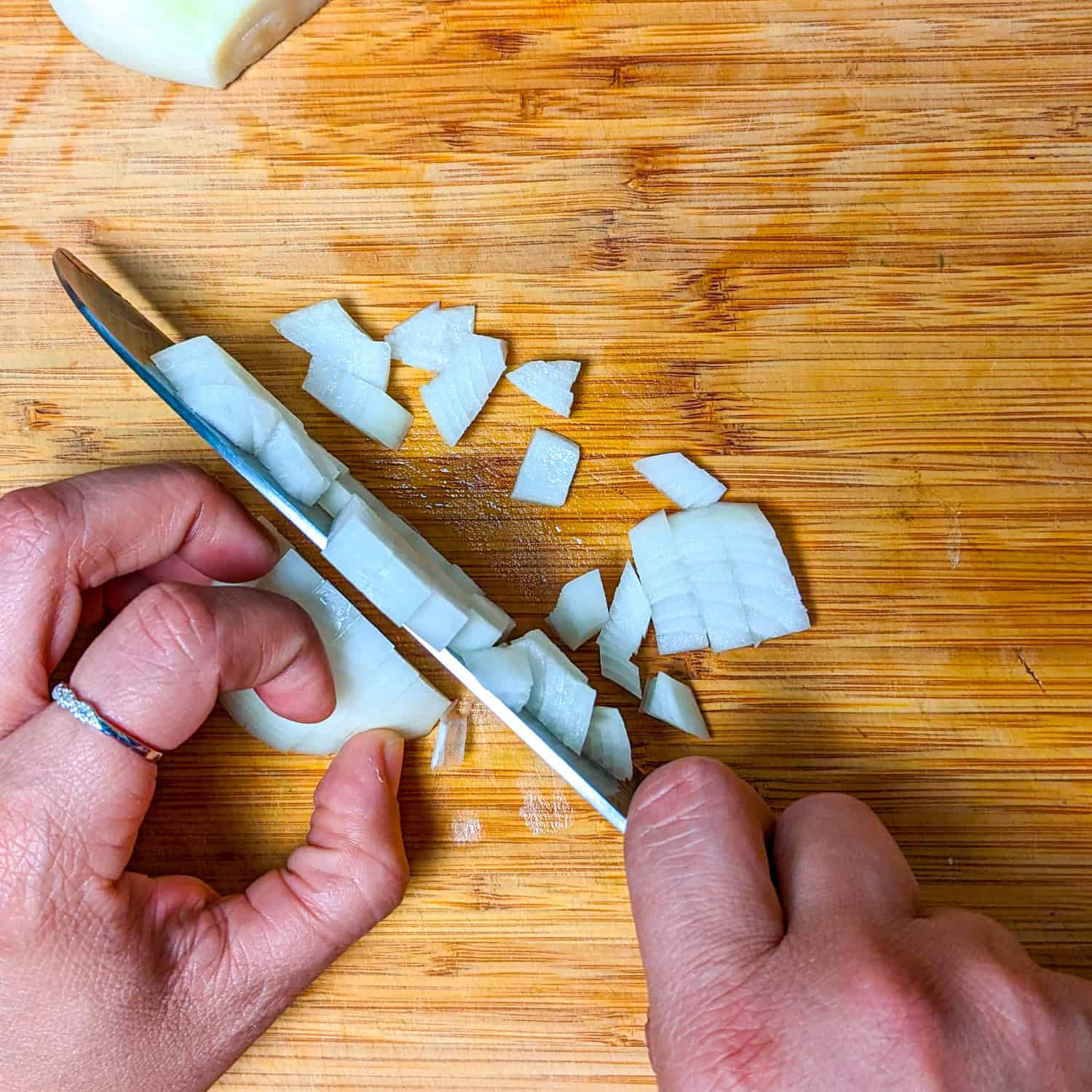 chopping the onions on a cutting board with a sharp knife.