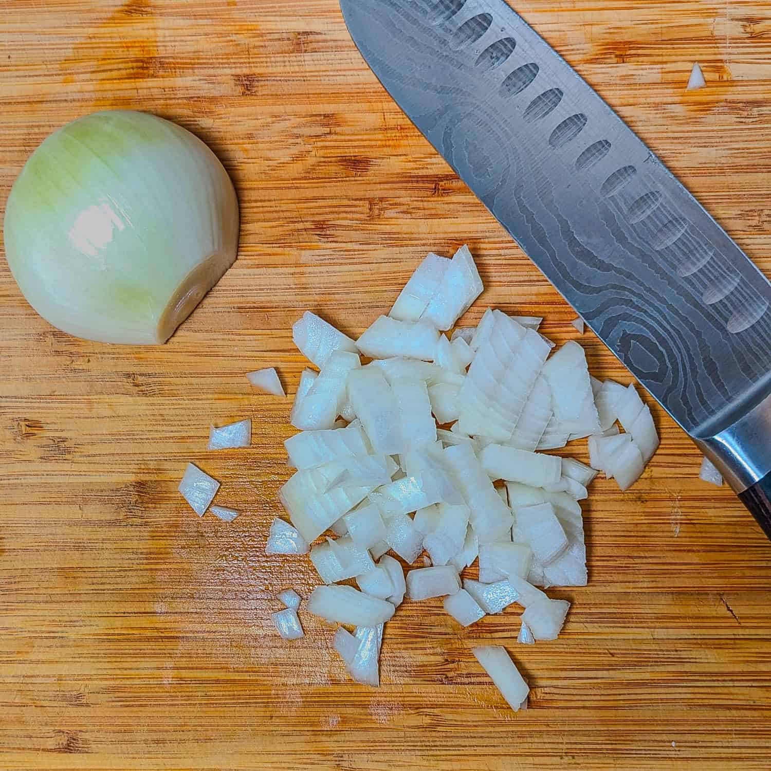 showing a halved onion next to chopped onions with the PAUDIN santoku knife next to it.